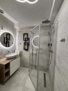 a bathroom with a glass shower and a sink at Apartamenty Sopot Karlikowo in Sopot
