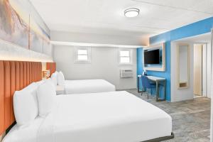 Habitación de hotel con 2 camas y escritorio en Tropicana Motel, en Wildwood