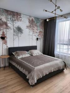1 dormitorio con 1 cama y una pared con árboles en Красивая квартира возле EXPO, Nexpo City en Astaná
