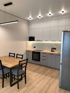 a kitchen with a table and chairs and a refrigerator at Красивая квартира возле EXPO, Nexpo City in Astana