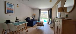 ein Wohnzimmer mit einem Tisch und einem blauen Sofa in der Unterkunft Centre du Val André - appart en rez de jardin avec terrasse et jardinet - plage à 150 m in Pléneuf-Val-André