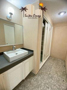 a bathroom with a sink and a mirror at Suites Omega Torres Gemelas in Acapulco