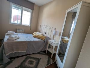 um pequeno quarto com uma cama e um espelho em Noly Apartamento em Monforte de Lemos