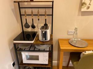 La cocina está equipada con un estante con utensilios y microondas. en Clay Farm Guest House en Bromley