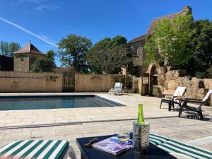 a bottle of wine sitting on a table next to a pool at Château de Monsac in Monsac