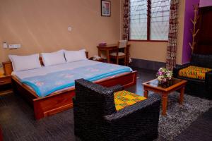 a bedroom with a bed and two chairs and a table at Dominion Embassy Lodge in Sekondi-Takoradi