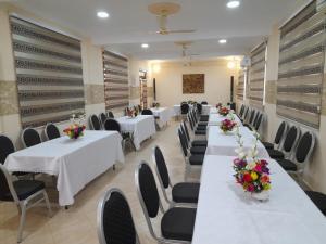 una fila de mesas en una habitación con mesas y sillas blancas en Dominion Embassy Lodge en Takoradi