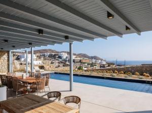 a patio with a table and chairs and a pool at Villa Meraviglia Elia Mykonos in Elia Beach