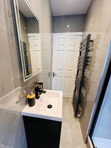 W białej łazience znajduje się umywalka i lustro. w obiekcie -R2- Newly Renovated Private self contained Room with Garden Access in Birmingham Selly Oak w Birmingham