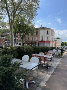 a group of tables and chairs on a sidewalk at HÔTEL PARIS VÉSINET- Logis Hôtel Restaurant in Le Vésinet