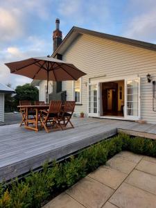 a wooden deck with two chairs and an umbrella at Number 32 in Taumarunui