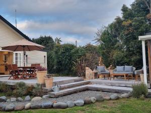 a patio with a table and chairs and an umbrella at Number 32 in Taumarunui +8 photos