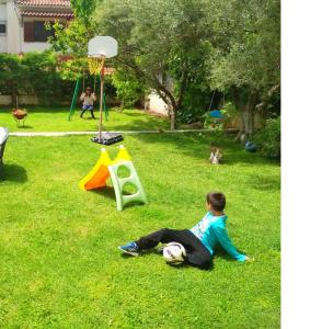 Ein kleiner Junge, der auf dem Gras neben einem Basketballkorb sitzt. in der Unterkunft Apartment Villa Panorama in Thessaloniki