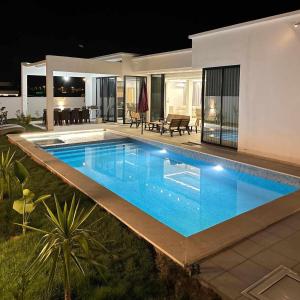 - une piscine en face d'une maison la nuit dans l'établissement villa Casa Luxe djerba, à Mezraya