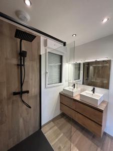 a bathroom with two sinks and a glass wall at Gite avec Spa Le Rubis proche des plages du Débarquement Manche Normandie in Joganville
