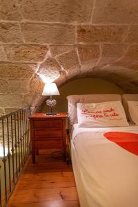 un letto in una stanza con un muro di pietra di Dimora Donna Maria a Polignano a Mare