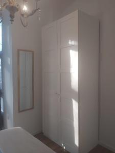 a white bedroom with a closet and a mirror at Buhardilla en el Cantón in Ferrol