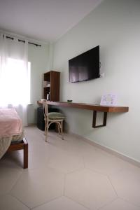 een slaapkamer met een bureau en een tv aan de muur bij MALUSI B&B in Napels