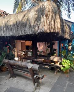 a hut with benches and a thatched roof at Pousada Bora Bora in Guarapari
