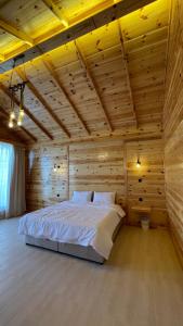ein Schlafzimmer mit einem großen Bett in einem Holzzimmer in der Unterkunft درة العروس اكواخ الدره in Durrat Al-Arus