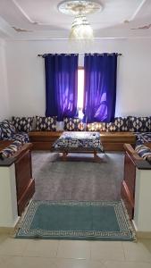 a living room with a couch and purple curtains at Warzazat Apartments in Ouarzazate