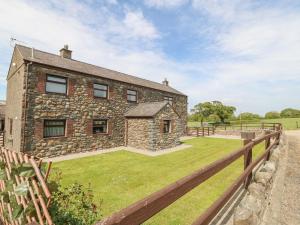 una casa in pietra con una recinzione di fronte di Yr Hen Stabl a Caernarfon