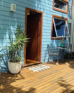 a porch of a blue house with a door and a table at Peixe Crew Manguinhos in Búzios