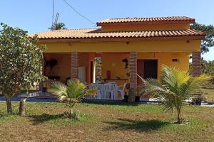 una pequeña casa amarilla con dos palmeras delante en Chácara Beira Rio - NX -MT, en Chavantina