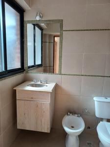 ein Badezimmer mit Waschbecken, Toilette und Spiegel in der Unterkunft Depto Del Centro in San Salvador de Jujuy