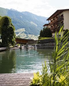 un lago frente a un edificio con montañas en el fondo en Naturhotel Outside, en Matrei in Osttirol