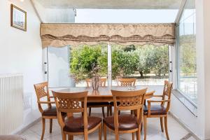 a dining room with a table and chairs and a window at Aegean Whispers House in Psalidi