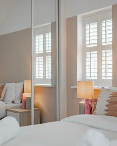 ein Schlafzimmer mit einem Spiegel, einem Bett und einem Sofa in der Unterkunft Stylish home w/ parkng, fst wifi in Cambourne