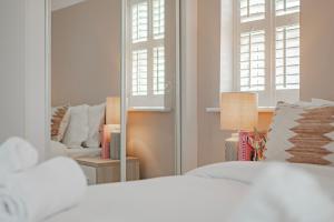 ein Schlafzimmer mit einem Spiegel, einem Bett und einem Stuhl in der Unterkunft Stylish home w/ parkng, fst wifi in Cambourne