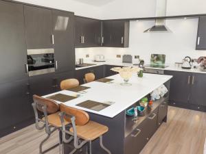 a kitchen with a large white island with chairs at Kingfisher Chalet in Chester