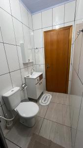 a bathroom with a toilet and a sink and a door at Casa do aconchego ( terreno compartilhado) in Foz do Iguaçu