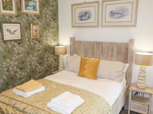 1 dormitorio con 1 cama con 2 lámparas y cuadros en la pared en Kingfisher Chalet en Chester