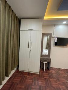 1 dormitorio con armario blanco y espejo en Applewood Inn en Katmandú