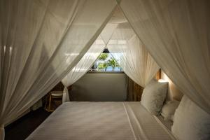 - une chambre avec un lit à baldaquin et des rideaux blancs dans l'établissement Le Coconut Lodge, à Avatoru