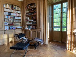 a living room with a chair and bookshelves at Beau château dans le Cantal au coeur du Pays Vert in Naucelles