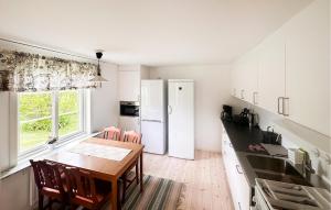 kuchnia z drewnianym stołem i kuchnia z białymi urządzeniami w obiekcie Stunning Home In Frjestaden With Kitchen w mieście Färjestaden