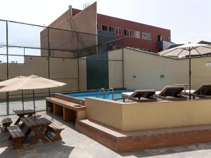 Una piscina con mesas y sombrillas al lado de un edificio. en Moderno 2BR Center Miraflores- Balta 301, en Lima