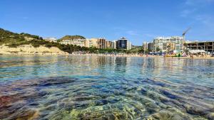 una masa de agua con una playa y edificios en Enorme apartamiento en CALA ALTA de Villajoyosa, en Cala de Finestrat