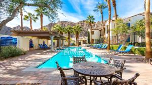 een terras met een tafel en stoelen naast een zwembad bij LV002 Secluded Downstairs Legacy Villas Studio in La Quinta