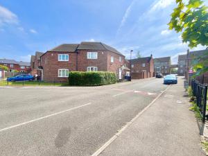 una calle vacía con casas de ladrillo y un coche azul en Payler House Sheffield-WiFi -Large Parking Space-cozy 4 bedrooms en Sheffield