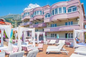 a hotel with chairs and umbrellas in front of a building at Accommodation Royal Azur in Dobra Voda