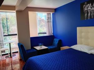 Dormitorio azul con cama, silla y ventanas en Munay Wasi CUSCO, en Cusco