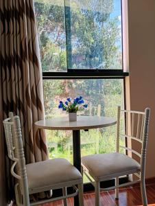 een tafel en twee stoelen voor een raam bij Munay Wasi CUSCO in Cuzco