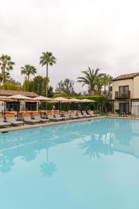 einen Pool mit Stühlen und Sonnenschirmen in einem Resort in der Unterkunft Estancia La Jolla Hotel & Spa in San Diego