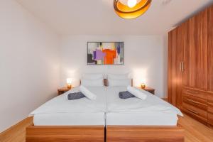 a bedroom with a large white bed with two lamps at Apartments L&D in Biograd na Moru