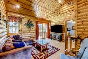 a living room with a couch and a tv in a log cabin at Getaway on the Green in Arkdale